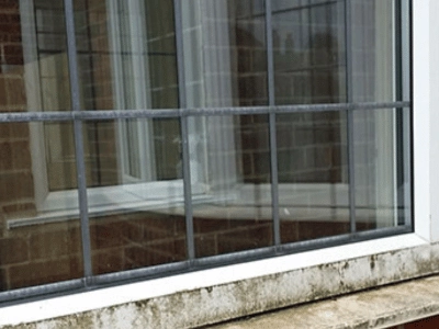 Professional window cleaner using a water fed pole on a modern new build house in the UK, showcasing window cleaning service